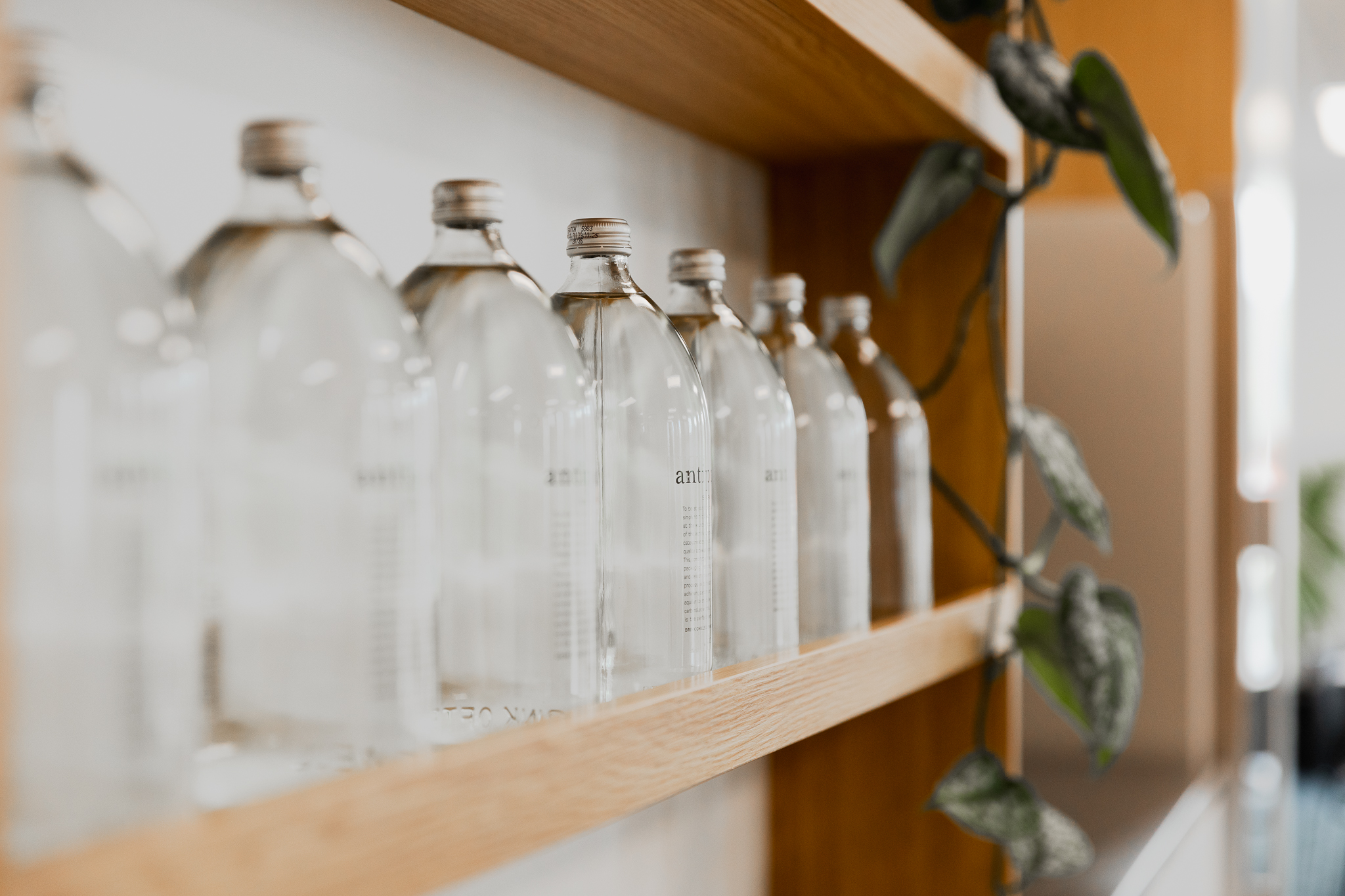 Reusable glass water bottles on a Q Space shelf
